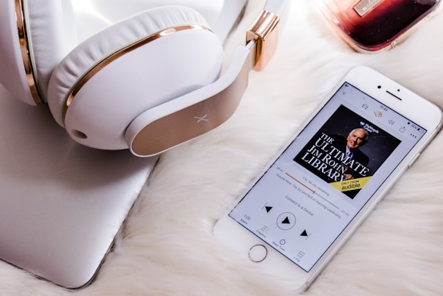 Headphones and smartphone with audiobook open on a fluffy platform