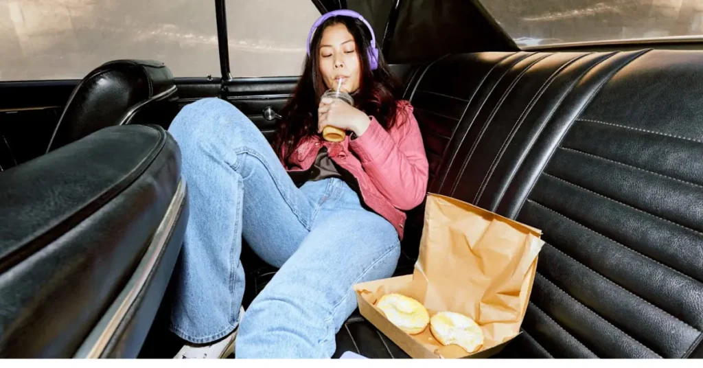 Nainen kuuntelee äänikirjoja auton takapenkillä